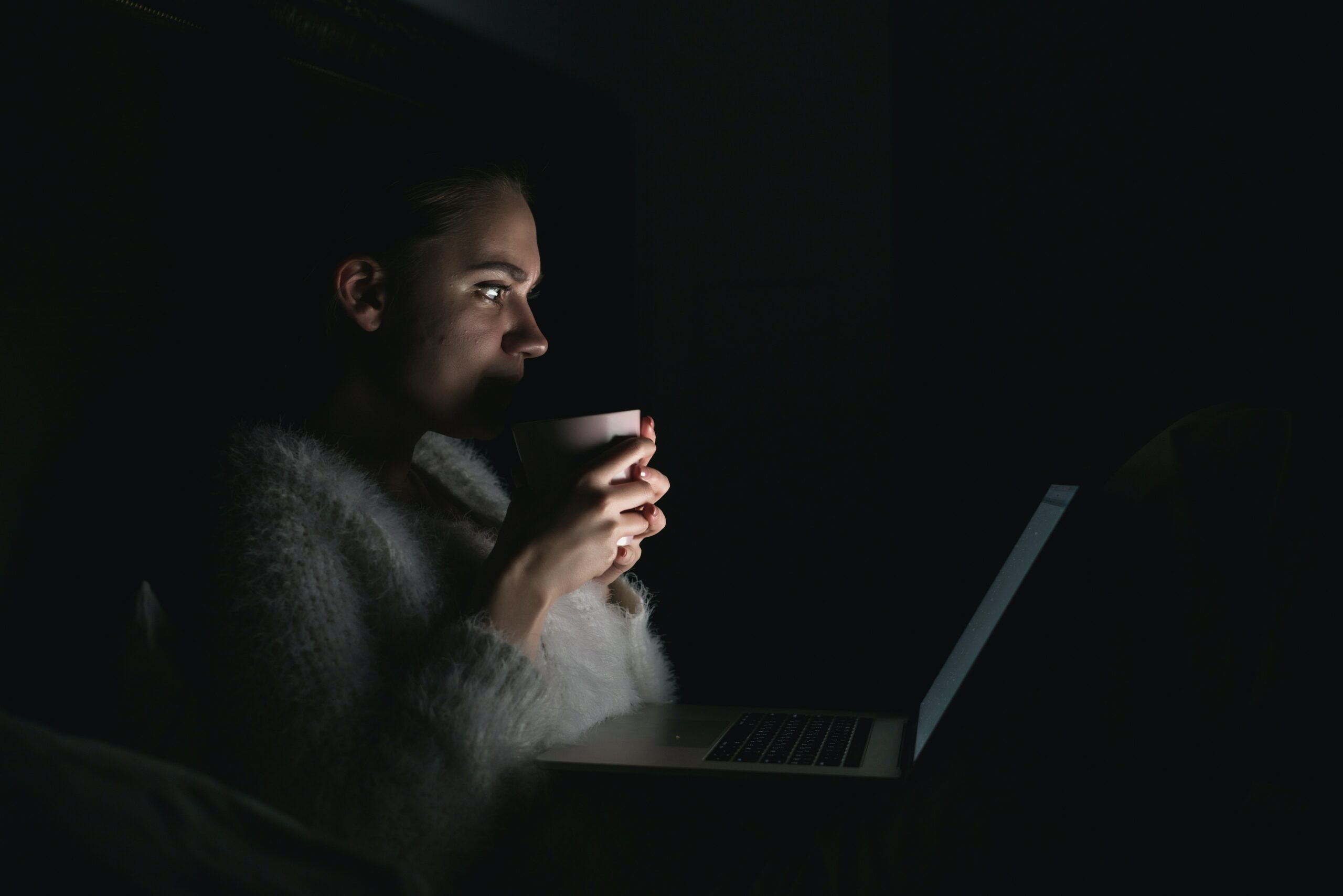 אישה מול המחשב הנייד בחושך